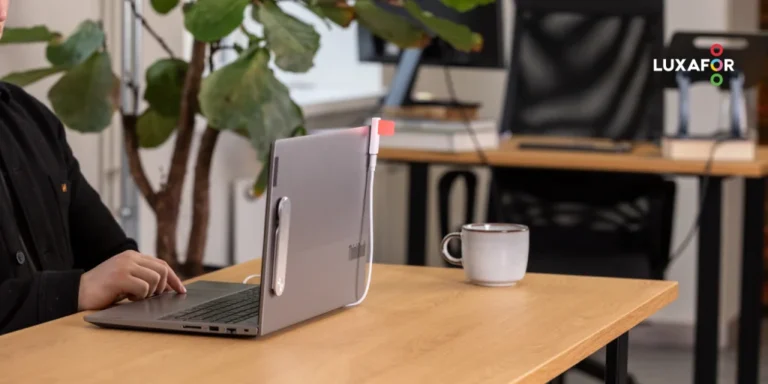 Open hybrid office with a busy light glowing red attached to a laptop monitor visualizing effective office space utilization.